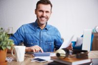 Portrait of smiling man calculating his monthly expenses